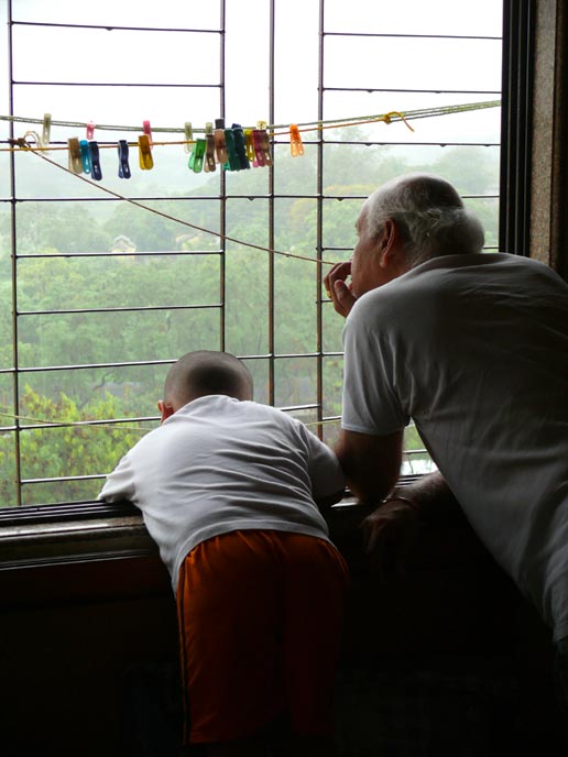 Locked up at home - An image of Manu and my father looking out of our bedroom window watching the rains on the 30th of June | copyright Picturejockey : Navin Harish 2005-2007