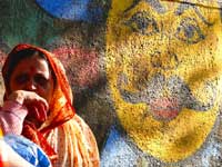 Woman and Sun - An image of a woman in Walkeshwar sitting in fron of an image of sun painted on a wall