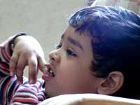Daaton tale ungli : Manu sitting with his finger between his teeth, watching TV