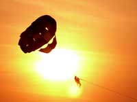 Parasailing at Calangute Beach, Goa : Two men parasailing with the sun in the background