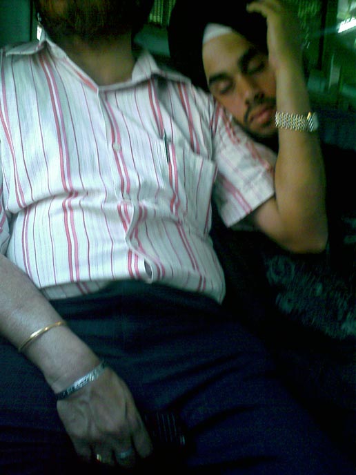 A young sardar boy sleeping on his father's shoulder on a Mumbai local train , copyright Picturejockey : Navin Harish 2005-2009